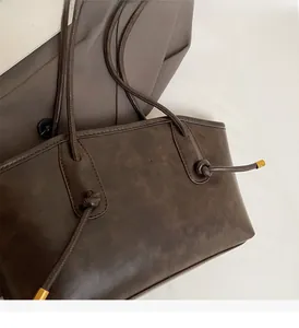 Detail of dark brown tote bag with knotted strap and gold metallic accents