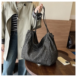 Detail of large leopard print tote bag with side pocket and canvas texture in cafe setting