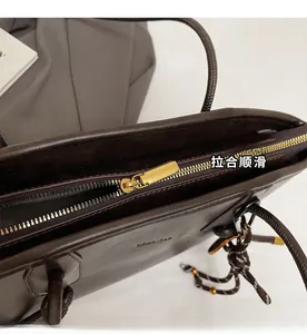 Detail of dark brown tote bag showing smooth faux leather and gold zipper closure