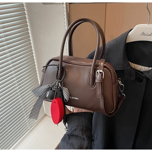 Detalle de bolso Boston vintage marrón con logo EAR K y colgantes de lazo ajedrez