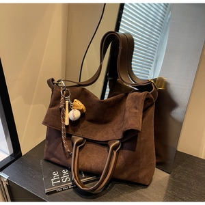 Dettagli materici della grande borsa tote marrone scamosciata con ciondolo da baseball