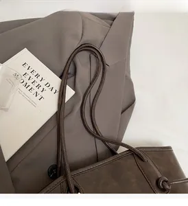Detailed view of dark brown tote bag with matte leather finish and double strap handle
