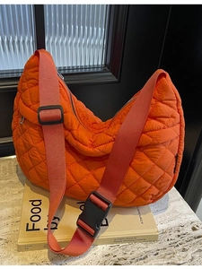 Sac à bandoulière matelassé orange vif avec sangle réglable sur présentoir en marbre