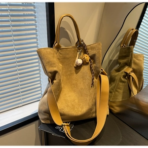 Dettaglio della borsa tote in pelle scamosciata con cinturini e ciondolo da baseball