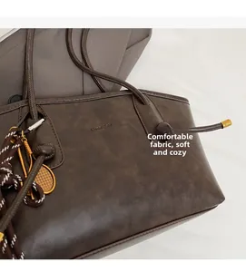 Detail of dark brown tote bag with vintage texture and golden tennis racket charm