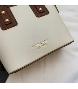 Detailansicht der Handtasche mit Kontrastfarben, goldenem Logo und Nieten-Details