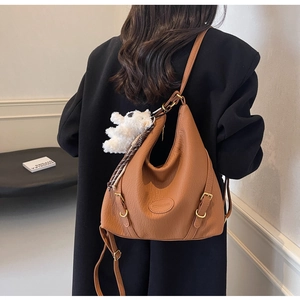 Brown lychee leather multi-way backpack detail with plush bear charm and gold buckle