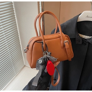 Detalle de bolso Boston marrón con colgante de bola de billar y lazo de cuadros