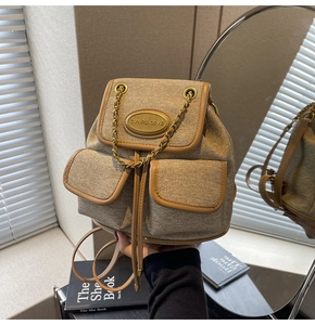 Détail du sac à dos en toile kaki avec bordure en cuir et plaque logo dorée chic