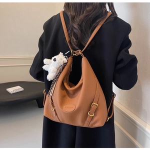 Detail of caramel brown faux leather backpack showing litchi texture and bear charm
