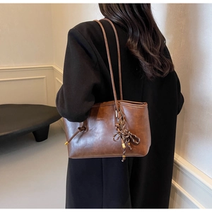 Detailed view of a brown vintage leather tote bag with elegant knot charm and gold hardware