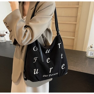 Detail of black corduroy tote bag featuring white embroidered Our Future lettering