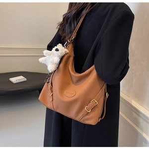 Brown faux leather shoulder bag with lychee texture and plush bear charm on model