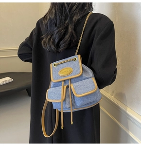 Détail du sac à dos en jean bleu avec garniture en cuir et bretelles en chaîne tissée