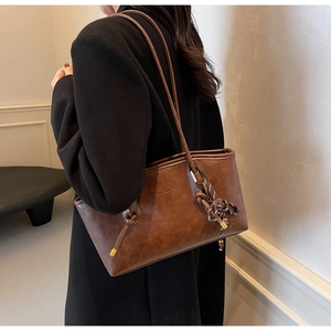 Detail of vintage brown leather tote bag with woven knot charm and slim shoulder straps