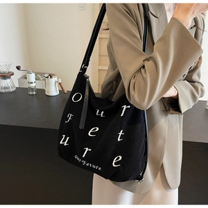 Macro detail of black corduroy tote with 'our Future' embroidery and leather strap