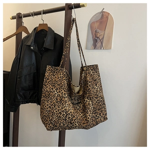 Detail of leopard print tote bag hanging on wooden rack in a modern interior setting