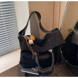 Dettaglio della borsa tote nera con doppi manici e accessorio con ciondolo da baseball