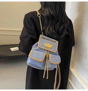 Mini sac à dos en denim bleu avec finitions en cuir porté par un mannequin