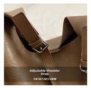 Detail of adjustable shoulder strap on dark brown PU leather bag with silver metal buckle