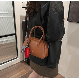 Bolso Boston vintage marrón con colgante rojo y bufanda usado por una modelo real