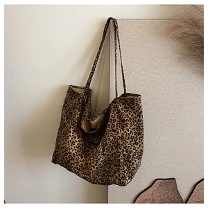 Detailed view of leopard print canvas tote bag hanging on wall with decorative dried flowers