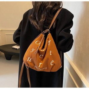 Close-up of brown corduroy tote bag showing 'our future' embroidery and leather strap