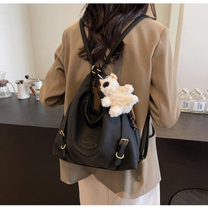 Detail of black pebbled leather multi-way backpack with gold hardware and plush bear charm