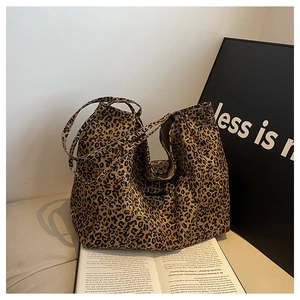 Detailed close-up of leopard print tote bag with thick handles on a vintage book