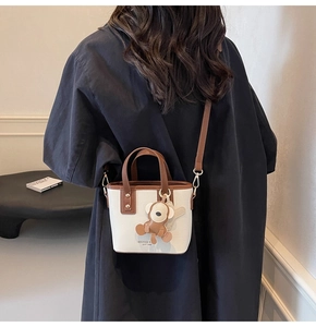Detailansicht der Mini-Beuteltasche mit Kontrastkante und Affen-Anhänger am Modell