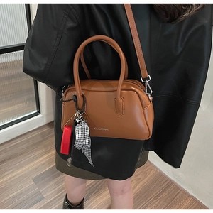 Detalle de bolso de cuero caramelo con pañuelo decorativo y logotipo de marca