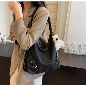 Close-up of black PU leather tote bag featuring gold buckle and cute white bear charm