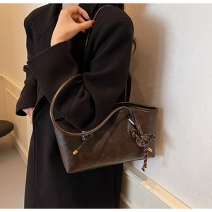 Detail view of dark brown leather tote bag with braided knot tassel and gold hardware accent