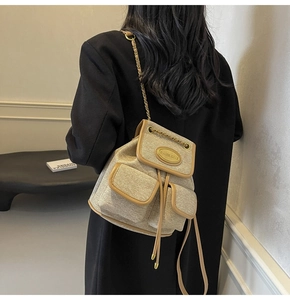 Détail d'un mini sac à dos en tweed avec chaînes dorées et finitions en cuir marron