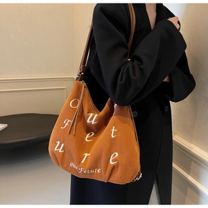 Detailed view of orange corduroy tote bag with Our Future embroidery and leather straps