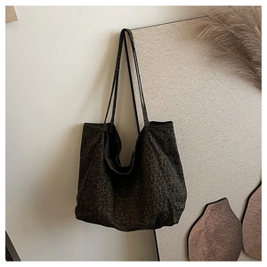 Detail shot of large leopard print tote bag with brown straps in a minimalist setting