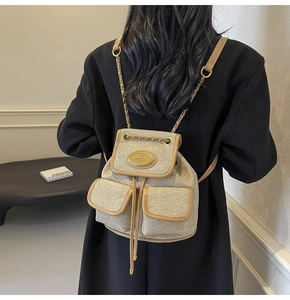 Détail du sac à dos à cordon en toile dorée avec garniture en cuir brun et chaînes