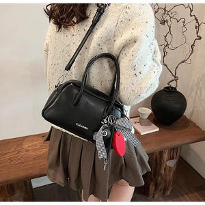 Detalle de bolso estilo almohada en cuero negro vintage con texto blanco y adornos