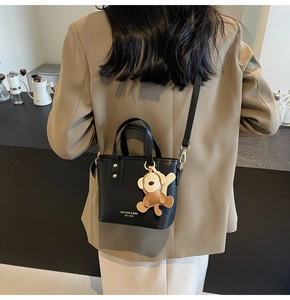 Details der schwarzen PU-Leder Eimertasche mit Goldbeschlägen und Affenanhänger