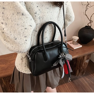 Detalle de bolso Boston negro en PU con lazo decorativo y correas plateadas