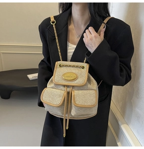 Détail d'un mini sac à dos en toile beige avec garniture en cuir brun et chaînes dorées
