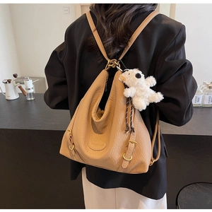 Detail of khaki leather multi-way backpack with soft texture and cute plush puppy charm