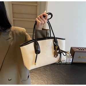 Detail of vintage beige tote bag featuring brown handles and tennis racket charm accessory
