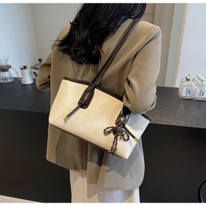 Detail of beige and coffee tote bag with knotted leather decor and bow pendant