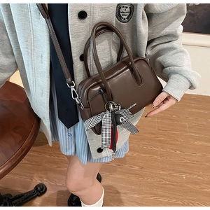 Detalle del bolso Boston vintage marrón con un lazo de cuadros y un colgante de billar
