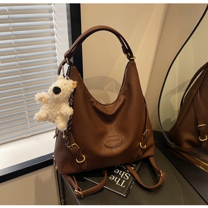 Close-up of brown lychee leather hobo bag with gold buckle and cute plush bear charm