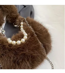Gros plan sur un sac en peluche marron avec anse en perles et chaîne en argent
