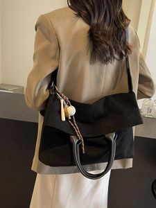 Grande borsa tote nera alla moda con ciondolo sportivo indossata da modella in completo beige
