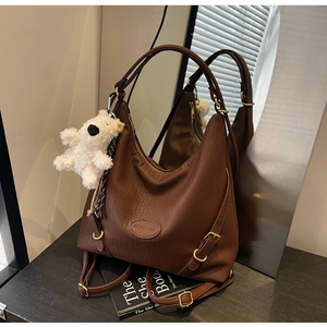 Detailed view of brown lychee grain leather hobo bag with teddy bear charm and gold hardware