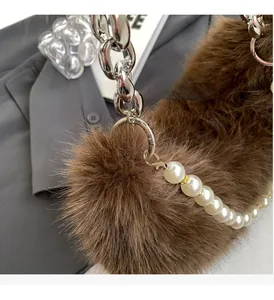 Détail de la texture en fausse fourrure marron avec chaîne argentée et perles élégantes